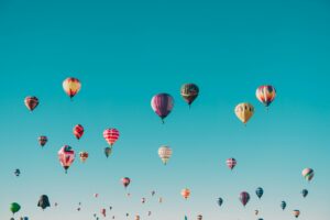 app developers hot air balloons of various colors and designs floating in a clear blue sky, much like the diversity found in mobile development and application development projects utilizing an mvp approach. tiny screen labs