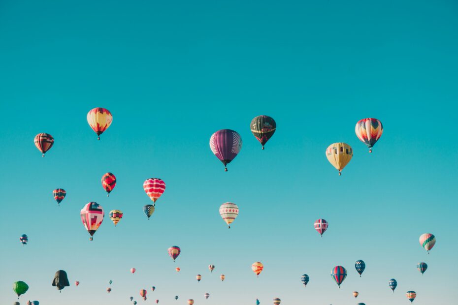 app developers hot air balloons of various colors and designs floating in a clear blue sky, much like the diversity found in mobile development and application development projects utilizing an mvp approach. tiny screen labs